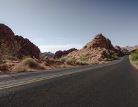 a motorcycle is driving through an desert area of a mountain range with rocks and scrub