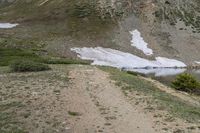 an outdoor area with a road, hill and a snowy field on the side of a mountain