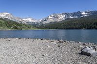 a scenic mountain lake surrounded by lush green hills and trees, near a gravel path