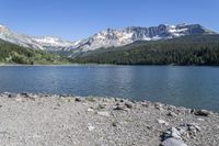 a scenic mountain lake surrounded by lush green hills and trees, near a gravel path