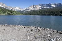 a scenic mountain lake surrounded by lush green hills and trees, near a gravel path