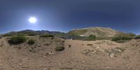 a panoramic view of the sun over a mountain range with a lake at the bottom