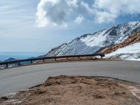 a snow covered road is near a very steep cliff on a clear day the wall is filled with snow and snow