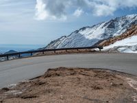 a snow covered road is near a very steep cliff on a clear day the wall is filled with snow and snow