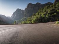 road next to large mountains on sunny day in the wilderness with bright sunbeams and blue sky