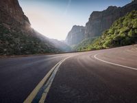 this is a long straight road between some cliffs with a canyon in the background as a car travels down it