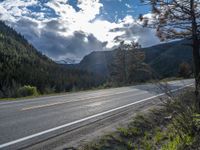 a person on a bike rides down the road with mountains in the distance along side of it