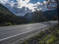 a person on a bike rides down the road with mountains in the distance along side of it