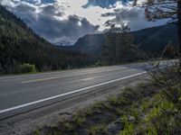 a person on a bike rides down the road with mountains in the distance along side of it