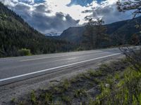 a person on a bike rides down the road with mountains in the distance along side of it