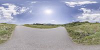 a panoramic image of a winding mountain road with mountains in the distance and blue sky