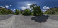 the view from a 360 - lens lens of an empty street in the mountains near some trees