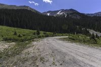 a wide view of a road going through a grassy area with a snow capped mountain in the background