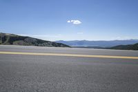 the empty road leading down to a scenic overlook on a mountain side with a sky background