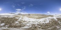 a small mountain surrounded by snow and dirt on a sunny day under a blue sky