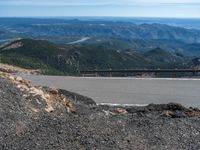 a snow covered road is near a very steep cliff on a clear day the wall is filled with snow and snow