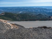 a snow covered road is near a very steep cliff on a clear day the wall is filled with snow and snow