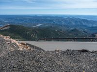 a snow covered road is near a very steep cliff on a clear day the wall is filled with snow and snow