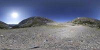 a landscape view looking up to a grassy mountain valley with some rocks and stones on the ground