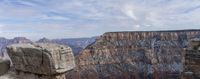 a man taking pictures in the distance with his camera while standing at a canyon rim