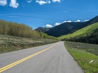 the road is paved with yellow markings and has a snowy mountain range in the background