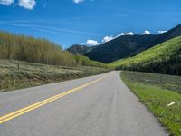 the road is paved with yellow markings and has a snowy mountain range in the background