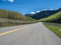 the road is paved with yellow markings and has a snowy mountain range in the background