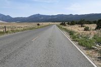 a man walks along a paved road towards the mountains in the distance, with no cars on the roadway