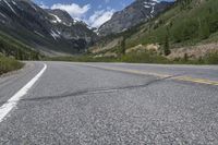 the road in front of the mountains is empty, with no cars on it that are visible