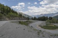 a motorcycle is riding on the road down to the mountain side by itself with trees on both sides, on a road, in the mountains and the distance are other mountains