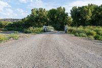 a rural country road is empty, and is blocked by an off - guard gate