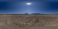 there is a field with some rocks and a sun above it, it's in the background