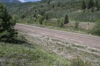 a motorcycle is parked on the road in the mountains near the grass field with trees