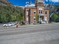 a big house with two fire trucks parked next to it and mountains in the background