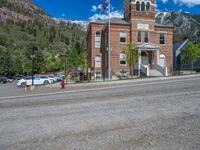 a big house with two fire trucks parked next to it and mountains in the background