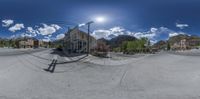 a 360 - degree fish eye view of an intersection with buildings and street signs on both sides