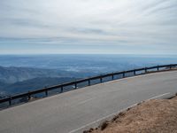 a man is riding his bike down a mountain road with snow and rocks in the background