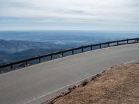 a man is riding his bike down a mountain road with snow and rocks in the background