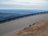 a man is riding his bike down a mountain road with snow and rocks in the background