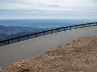 a man is riding his bike down a mountain road with snow and rocks in the background