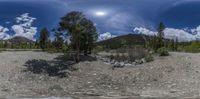 the camera's panoramic view of a dirt field and river with trees