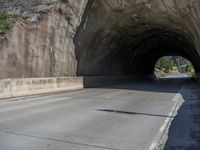 a road goes into a tunnel and through the hill to the other side of it