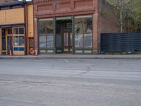 a red fire hydrant sitting in front of an old store window and building next to an open air field