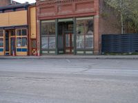 a red fire hydrant sitting in front of an old store window and building next to an open air field