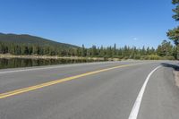 the road near a large body of water has trees on it's sides and a sign hanging off the side of it says don't - up