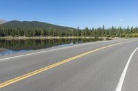 the road near a large body of water has trees on it's sides and a sign hanging off the side of it says don't - up