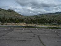 a mountain sits in the distance in a parking lot with a few trees and shrubbery