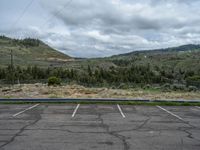 a mountain sits in the distance in a parking lot with a few trees and shrubbery