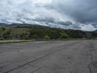 a mountain sits in the distance in a parking lot with a few trees and shrubbery