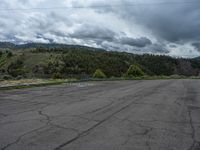 a mountain sits in the distance in a parking lot with a few trees and shrubbery